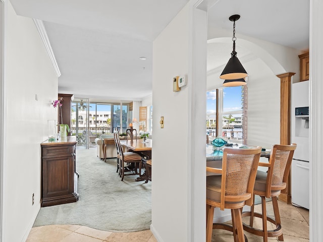 dining room featuring arched walkways, plenty of natural light, light colored carpet, and crown molding