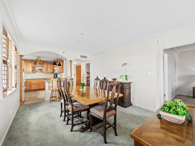 dining room featuring visible vents, arched walkways, light colored carpet, and crown molding