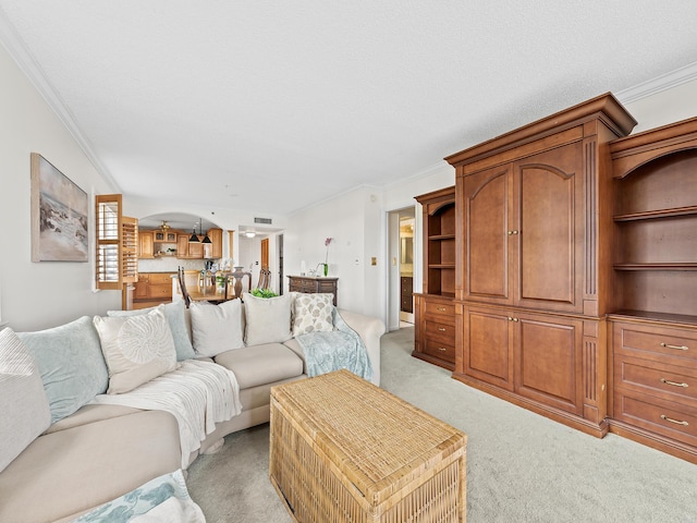 living area with crown molding, light colored carpet, and arched walkways