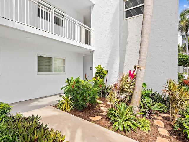 entrance to property with stucco siding and a balcony