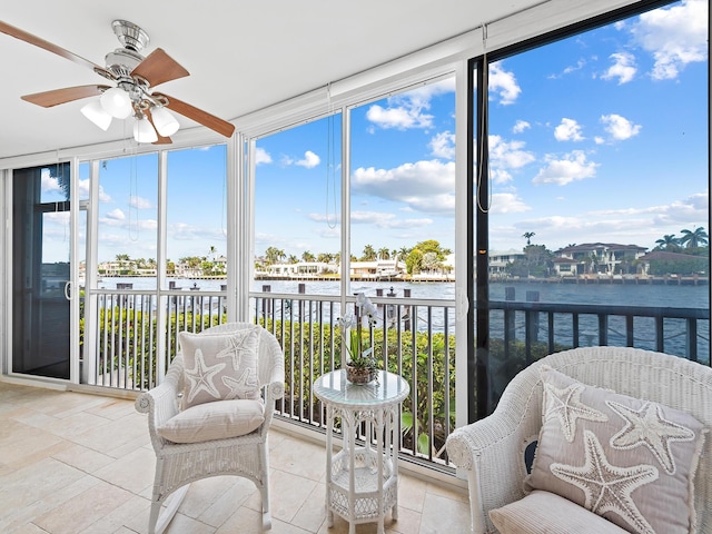 sunroom featuring a water view and a ceiling fan