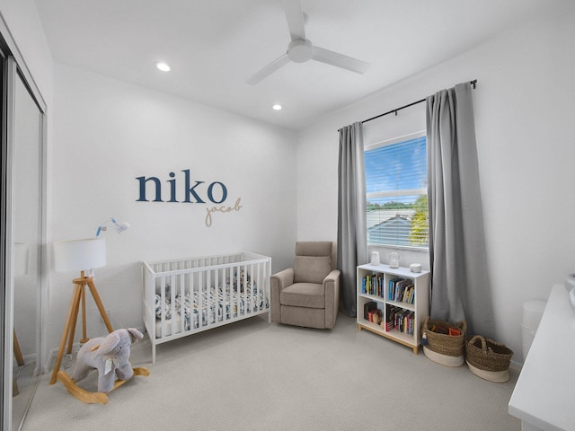 bedroom with recessed lighting, ceiling fan, a nursery area, a closet, and carpet flooring