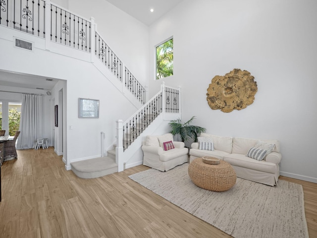 living area with a wealth of natural light, a high ceiling, and wood finished floors