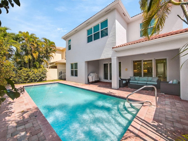 rear view of property with a patio, an outdoor pool, stucco siding, outdoor lounge area, and a tiled roof