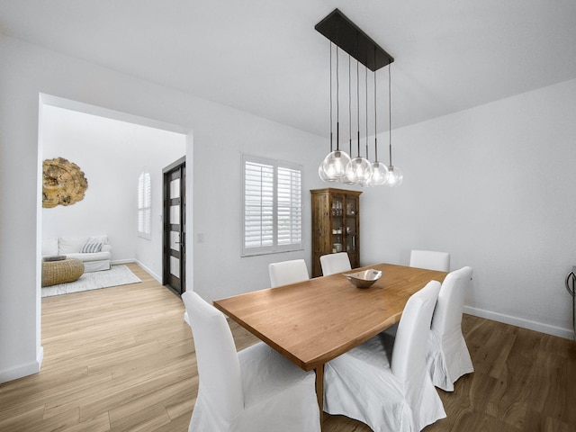 dining area with an inviting chandelier, light wood-style floors, and baseboards