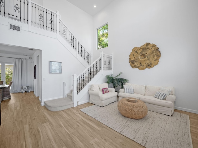 living room featuring stairway, a high ceiling, a wealth of natural light, and wood finished floors