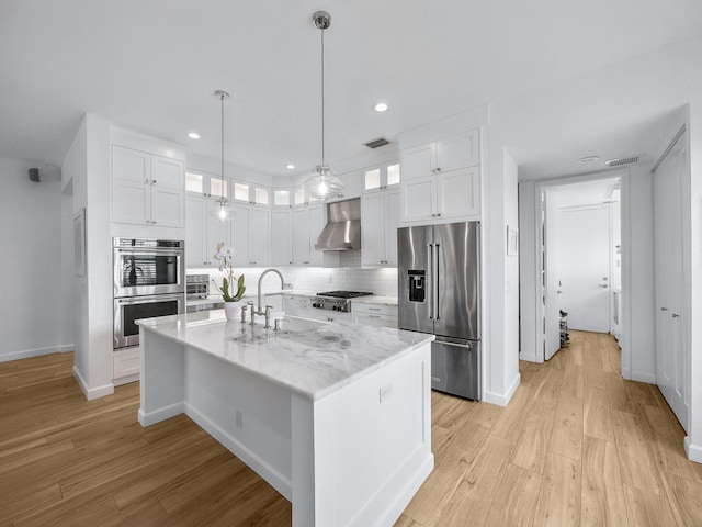 kitchen with stainless steel appliances, white cabinetry, visible vents, and wall chimney range hood