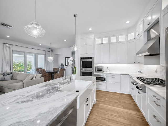 kitchen with visible vents, a sink, open floor plan, stainless steel appliances, and extractor fan