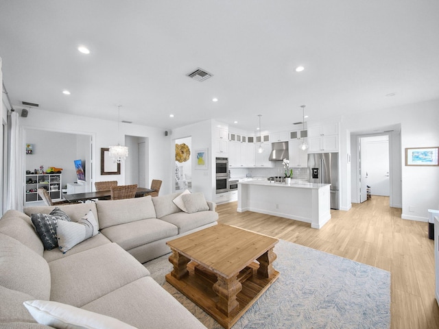 living area with visible vents, baseboards, an inviting chandelier, recessed lighting, and light wood-style floors