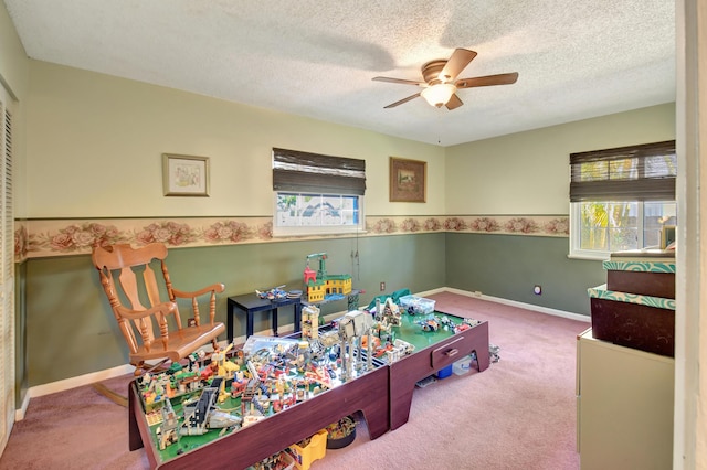 recreation room with baseboards, carpet flooring, a textured ceiling, and ceiling fan