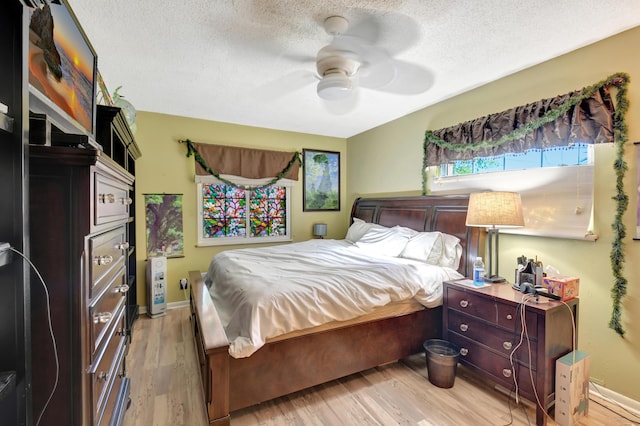 bedroom with baseboards, a textured ceiling, light wood-type flooring, and ceiling fan