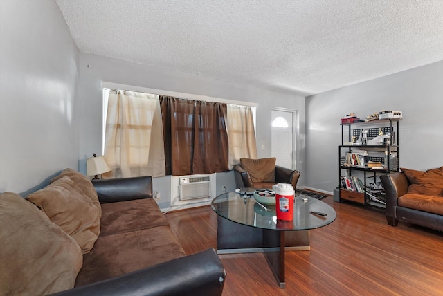 living room featuring cooling unit, wood finished floors, and a textured ceiling