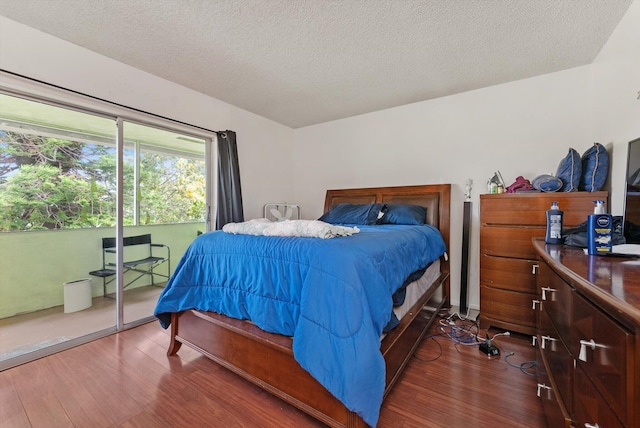 bedroom featuring access to outside, a textured ceiling, and wood finished floors