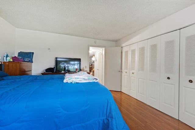 bedroom with a closet, a textured ceiling, and wood finished floors