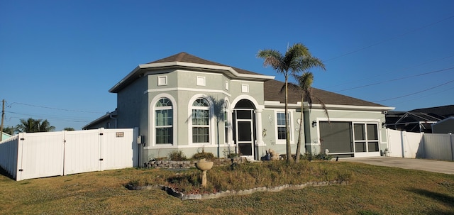 view of front of home with stucco siding, fence, a front lawn, and a gate