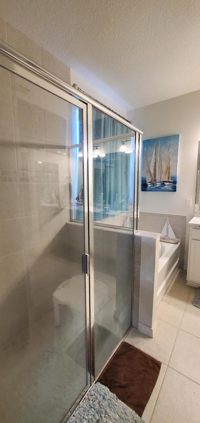 full bath with vanity, a stall shower, tile patterned flooring, a textured ceiling, and a bath