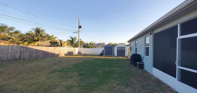 view of yard with an outbuilding, a storage unit, and a fenced backyard