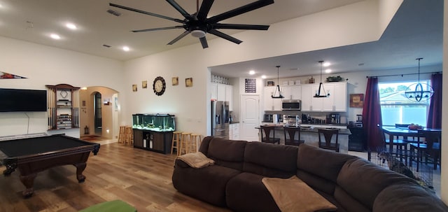 living room featuring billiards, wood finished floors, visible vents, arched walkways, and ceiling fan with notable chandelier