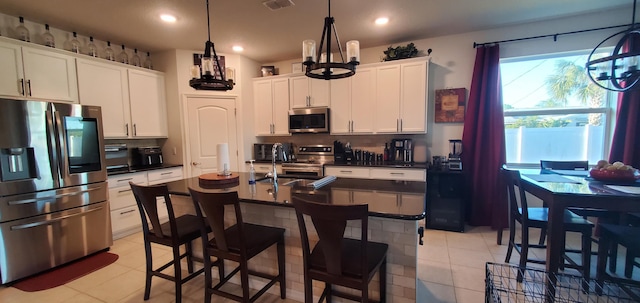 kitchen featuring a sink, appliances with stainless steel finishes, white cabinetry, dark countertops, and a notable chandelier