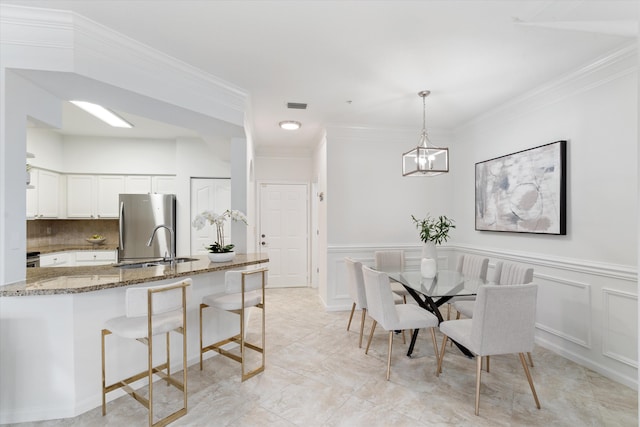 826 Dakota Dr Unit 105, Jupiter, FL 33458 - dining room with a decorative wall, crown molding, a wainscoted wall, and a chandelier