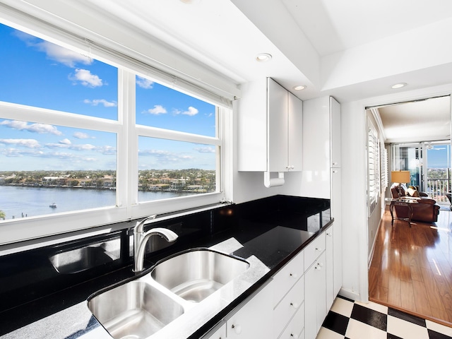 kitchen featuring white cabinetry, tile patterned floors, a water view, and a sink