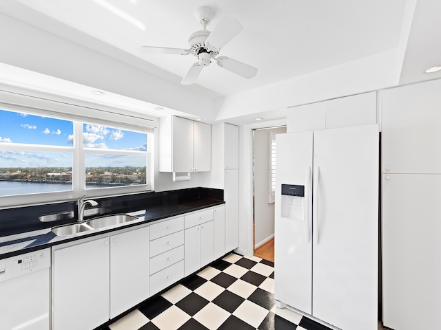 kitchen featuring white appliances, light floors, a sink, white cabinetry, and dark countertops