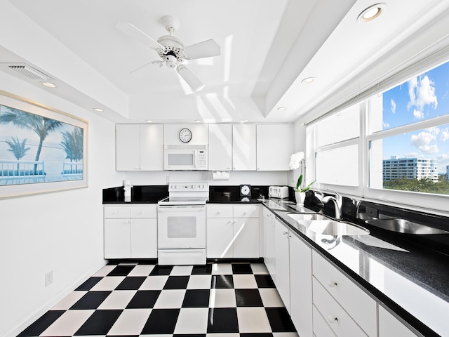 kitchen with white appliances, visible vents, a sink, dark countertops, and dark floors