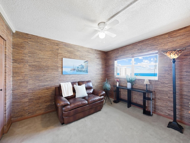 living area with a textured ceiling, ceiling fan, and carpet floors