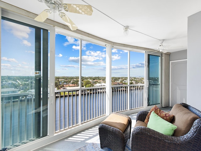 sunroom / solarium with a ceiling fan and a water view