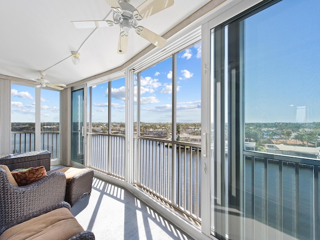 sunroom featuring ceiling fan and a water view