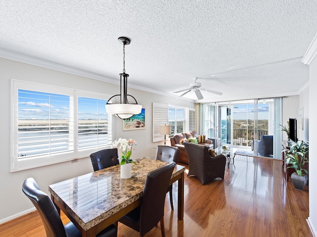 dining space featuring ornamental molding, a textured ceiling, ceiling fan, and wood finished floors