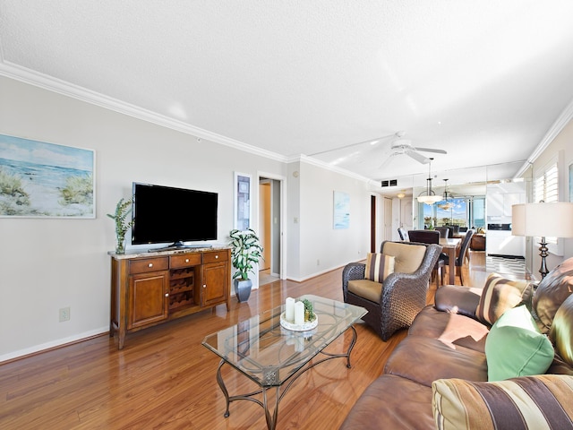 living room with light wood-type flooring, baseboards, a ceiling fan, and crown molding