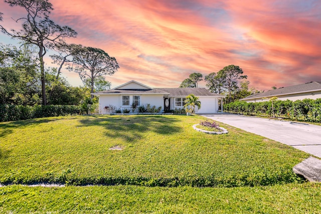 ranch-style home featuring an attached garage, concrete driveway, and a front yard