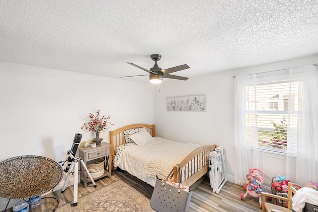 bedroom featuring baseboards, a textured ceiling, a ceiling fan, and light wood-style floors