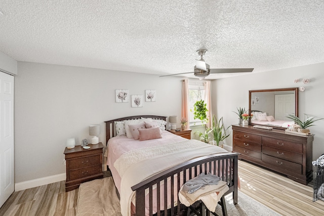 bedroom with a textured ceiling, baseboards, light wood-type flooring, and ceiling fan