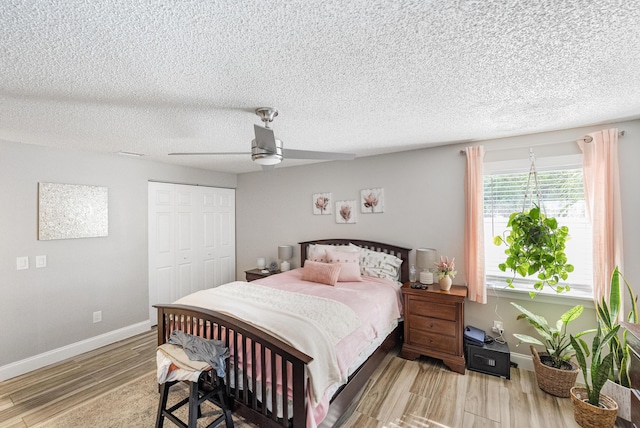 bedroom featuring a ceiling fan, baseboards, light wood-style flooring, a closet, and a textured ceiling