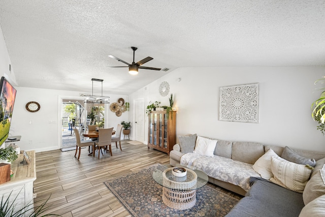 living area with light wood finished floors, visible vents, ceiling fan, lofted ceiling, and a textured ceiling