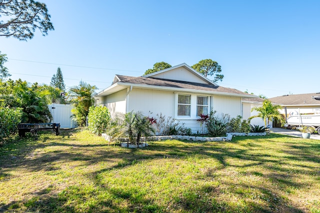 view of home's exterior with an attached garage, a yard, and fence