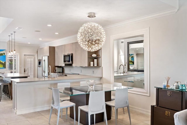 kitchen with stainless steel microwave, crown molding, light countertops, a peninsula, and a notable chandelier