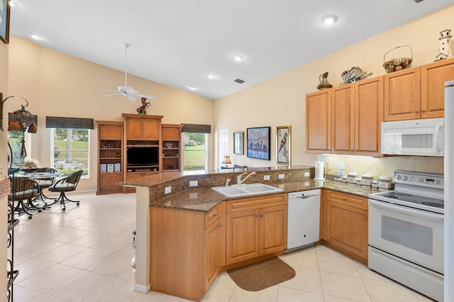 kitchen featuring white appliances, light tile patterned flooring, a peninsula, and a sink