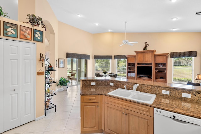 kitchen featuring a wealth of natural light, arched walkways, white dishwasher, light tile patterned flooring, and a sink