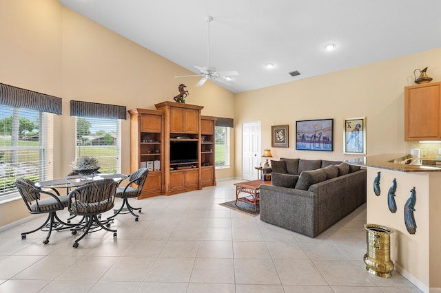 living room featuring light tile patterned floors, a ceiling fan, baseboards, visible vents, and high vaulted ceiling