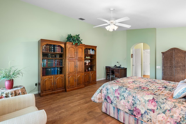 bedroom with visible vents, ceiling fan, baseboards, light wood-style floors, and arched walkways