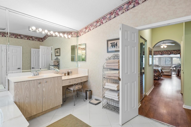 full bathroom featuring wallpapered walls, ensuite bath, tile patterned flooring, ceiling fan, and vanity