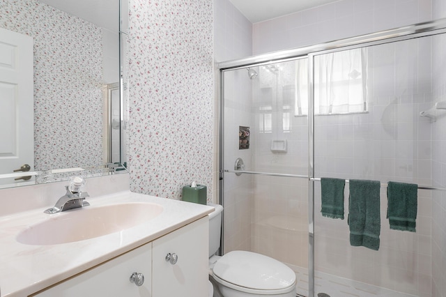 bathroom with a shower stall, wallpapered walls, toilet, and vanity