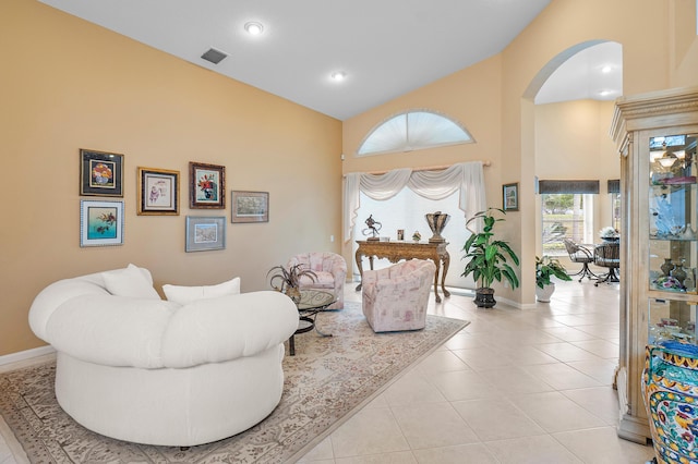 living room with light tile patterned floors, visible vents, baseboards, and arched walkways