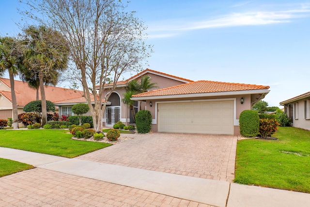 view of front of house with a tiled roof, a front yard, stucco siding, decorative driveway, and an attached garage