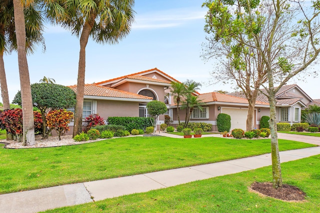 mediterranean / spanish house featuring stucco siding, a garage, a front yard, and a tile roof