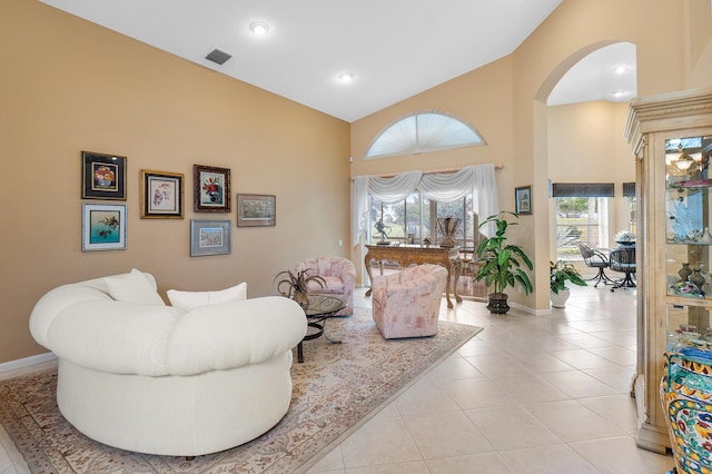 living room with light tile patterned flooring, visible vents, arched walkways, and baseboards