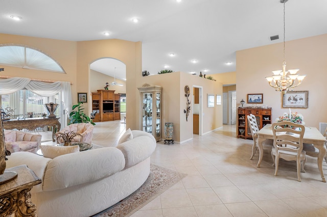 living area with visible vents, light tile patterned floors, an inviting chandelier, arched walkways, and high vaulted ceiling